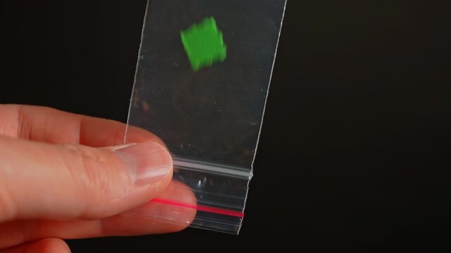 Drug dealer with LSD acid paper squares packed in small bag for sale, controlled drugs. Hallucinogenic psychedelic substances used in party and dance clubs.