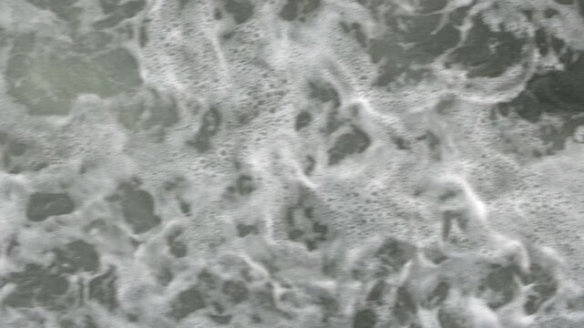 Top-down view of foamy ocean waves from a moving ship deck. Natural sea motion, textured water, and calming maritime atmosphere.