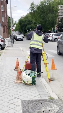 Topograf&iacute;a y top&oacute;grafo con c&aacute;mara y tr&iacute;pode midiendo y tomando medidas en la calle con chaleco y conos en acera