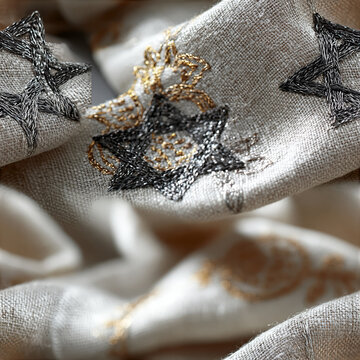 Soft draped linen cloth with dark silver embroidered Stars of David and fine gold thread details