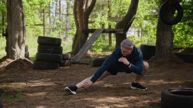 Young adult Caucasian man performing side lunge stretches at outdoor gym. Footage is ideal for fitness apps, health campaigns, and athletic lifestyle advertisements