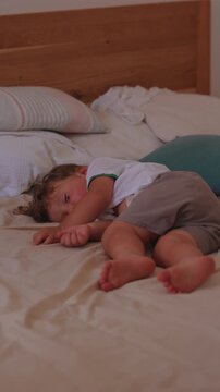Toddler sleeping peacefully on bed at home, briefly brushing away fly while remaining asleep, capturing deep rest, natural behavior and authentic childhood