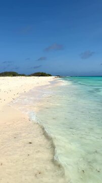 Turquoise ocean waves lapping on a pristine white sand beach in Klein Curacao