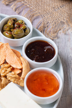 Close-Up View of Jams, Seasoned Green Olives, Dried Apples, and Walnuts on Breakfast Platter