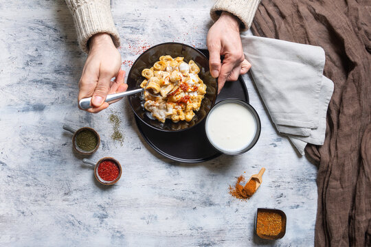 Top-Down View of male Person Eating Turkish Manti Dumplings with Spices and Yogurt