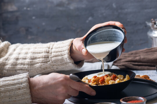 Pouring Garlic Yogurt Sauce Over Turkish Manti Dumplings