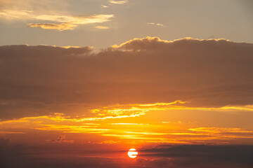 Fototapeta premium Bright sunset with orange clouds and sun on the horizon