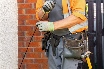 Close-up of telecoms engineer pulling fibre drop cable by hand © Tosh Lubek