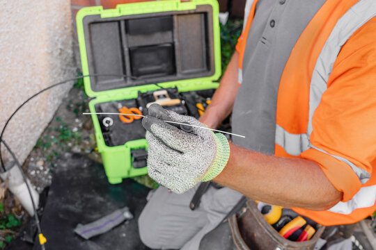 Engineer holds exposed fibre optic strand stripped from drop cable