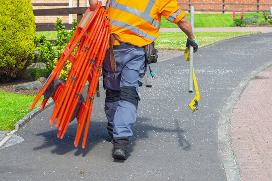 Telecoms engineer carrying barriers and tools after completing street works