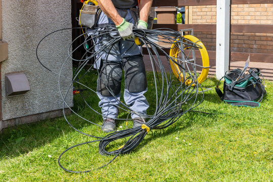 Telecoms engineer gathering old copper cable from lawn for recycling