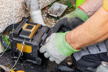 Telecoms engineer handling fusion splicer machine during FTTP broadband installation © Tosh Lubek