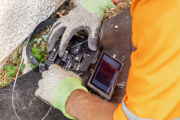 Telecoms engineer loading bare fibre into open fusion splicer during FTTP installation © Tosh Lubek