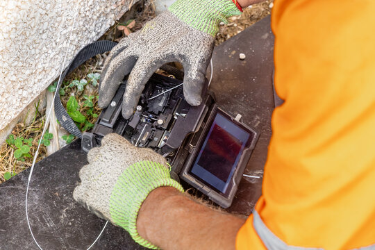 Telecoms engineer loading bare fibre into open fusion splicer during FTTP installation