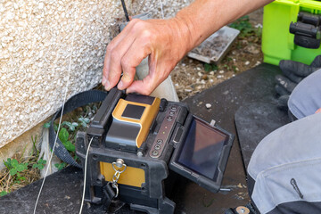 Telecoms engineer closing into heat shrink sleeve oven on fusion splicer lid during FTTP installation © Tosh Lubek