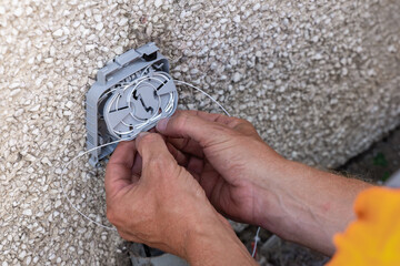 Telecoms engineer coiling spliced fibre into exterior wall entry bracket splice tray © Tosh Lubek