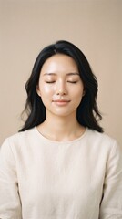 Fototapeta premium Serene Asian woman with eyes closed in meditation, peaceful female portrait with glowing skin, calm mindfulness and wellness concept on beige background