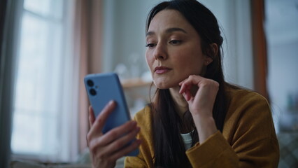 Fototapeta premium Brunette worried cellphone message receiving bad news in evening home closeup