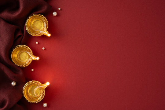 Happy Diwali celebration with traditional gold diyas on red vertical background and rich silk fabric