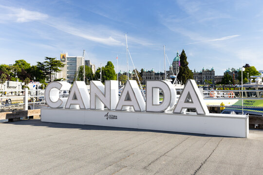 Victoria, BC, Canada - June 5, 2025: A Canada sign in downtown Victoria on the Victoria Harbor with boats and the Legislative Assembly of British Columbia in the background.