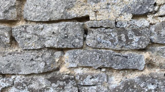 Panning video footage of an ancient stone wall made of Vesuvius yellow tuff and volcanic rock. Historic Neapolitan architectural background, traditional masonry craftsmanship.