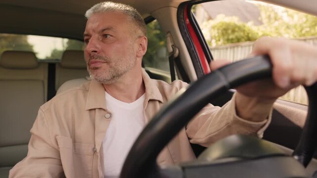 Focused man driving car in reverse,hand on wheel, 4K