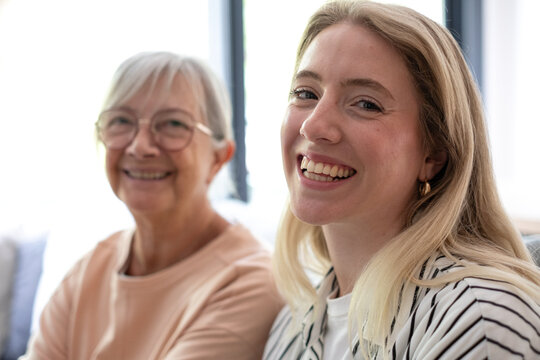 Happy senior woman and young adult woman smiling at home, embracing multi-generational family bonding and strong female connection