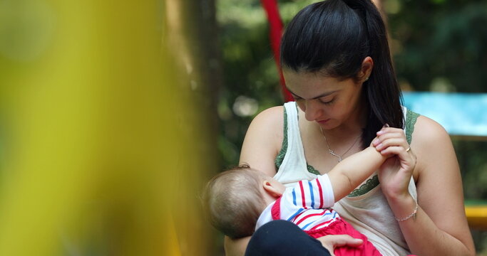 Candid mother holding baby infant boy outside at park