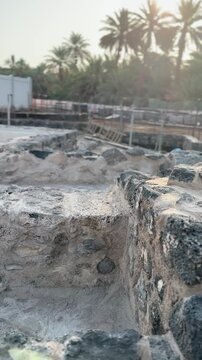 Ancient stone ruins and modern construction site at a palm oasis.