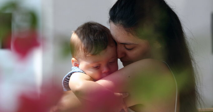 Candid mother holding tenderly infant baby son