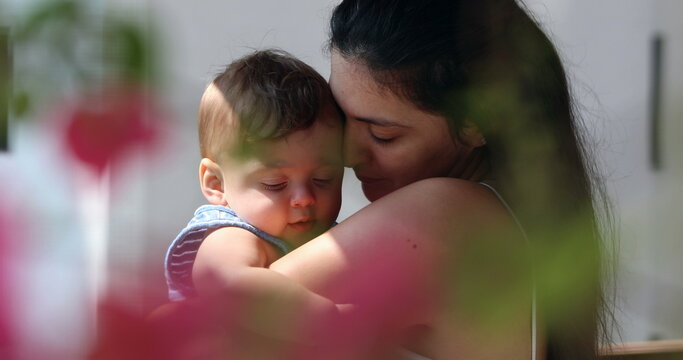Candid mother holding tenderly infant baby son