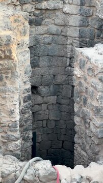 Deep ancient stone well and active archaeological excavation site with a ladder.