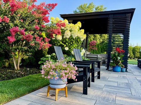 Gorgeous country cottage style border garden in among a modern, sleek, luxury outdoor patio living space equipped with a pavilion, pergola, cabana, pool, chaise lounge, fire pit, hot tub, sofa.