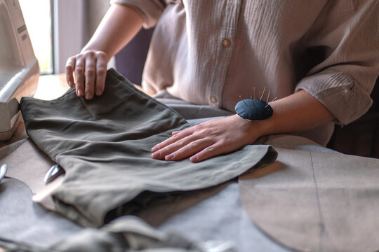 woman hand sewing fabric at home beside a sewing machine, creating or repairing clothing in a sustainable slow fashion, upcycling and handmade design