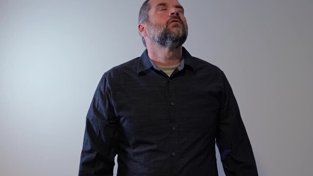 Middle aged adult man worried, concerned, anxious on gray background - Stressed worker feeling overwhelmed representing workplace burnout and crisis