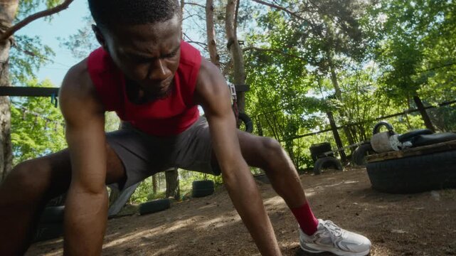 Dutch roll shot of African American young adult man stretching legs and warming up at outdoor gym. Clip is perfect for fitness advertisements, health campaigns, and athletic training promotions