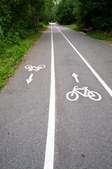 Obraz premium Bicycle path marked with lines and symbols in a green park during daytime