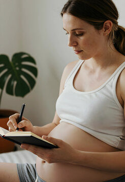 Pregnant woman journaling indoors in peaceful setting