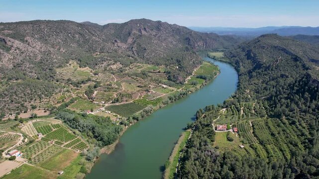 Forward reveal aerial shot of Ebro river on sunny spring day. Benifallet, Tarragona, Spain.