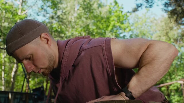 Young adult Caucasian man doing push-ups on wooden beam outdoors in slow motion. Ideal for fitness apps, healthy lifestyle promotions, and athletic training advertisements