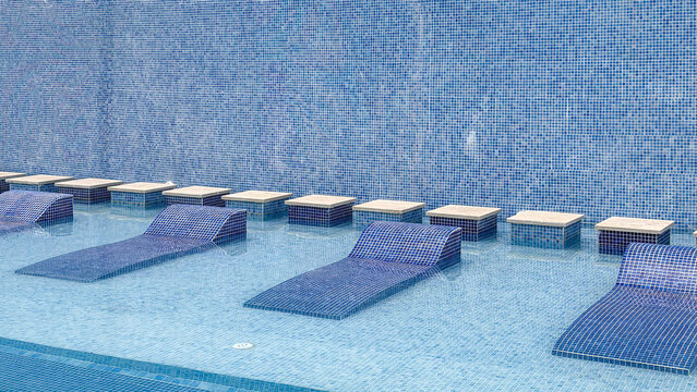 Luxury submerged pool loungers in shallow swimming pool at modern resort