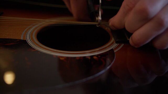 Luthier Cutting Old Acoustic Guitar Strings with Wire Cutters During Restringing Shot with Cinema Camera