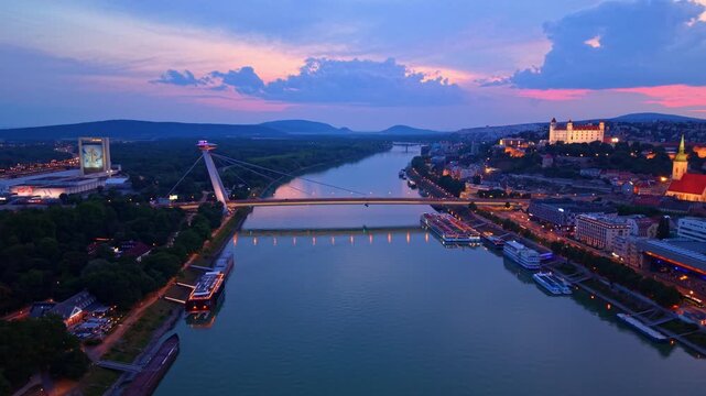 Danube river in bratislava. The video shows the Danube River flowing in Bratislava during sunset with bridges and buildings along the banks.