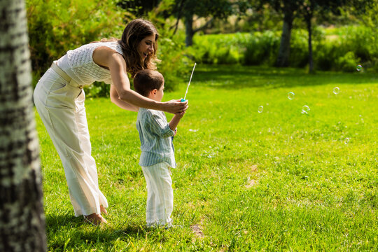 Mother and son blowing bubbles outdoors enjoying summer playtime