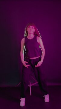 Young woman dancing hip hop in a dark studio with purple light