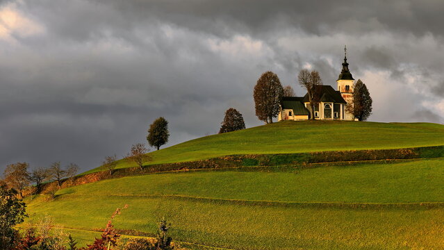 Sorrowful Mother of God church (Cerkev Žalostne Matere Božje) on a hilltop of the Prealps in a cloudy but sunlit, autumn dawn. Bukov Vrh-Slovenia-185