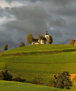 Sorrowful Mother of God church (Cerkev Žalostne Matere Božje) on a hilltop of the Prealps in a cloudy but sunlit, autumn dawn. Bukov Vrh-Slovenia-186