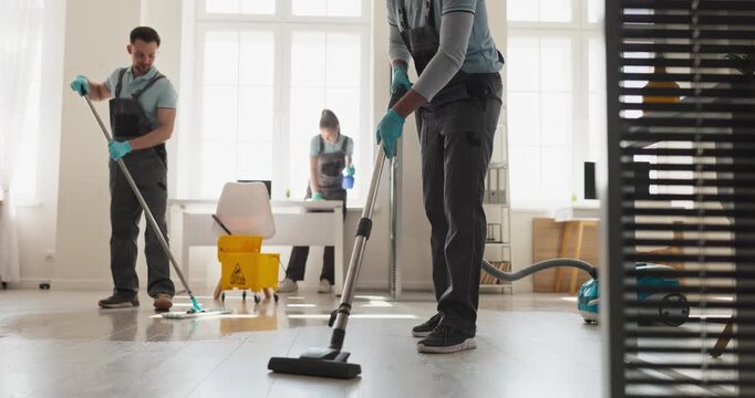 Cleaners janitors team cleaning office floors professionally. Uniformed staff mop and vacuum the workplace for daily hygiene and maintenance. Clear office sanitation service concept image.