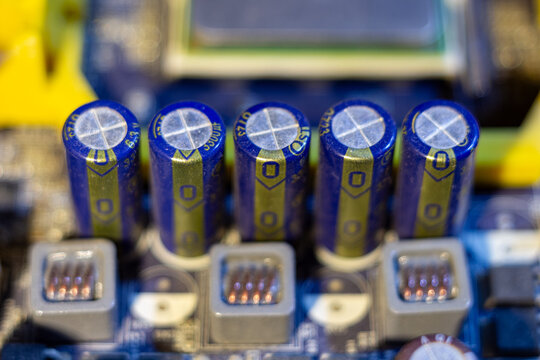 Five blue electrolytic capacitors on a motherboard circuit board component