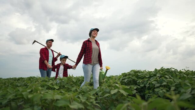 Farmer family outdoor in soybean field. Parents and child holding hand with hoe sprinkler. Family farm teamwork in soybean field. family bonding hoe sprinkler. Farmer family work outdoor soybean field